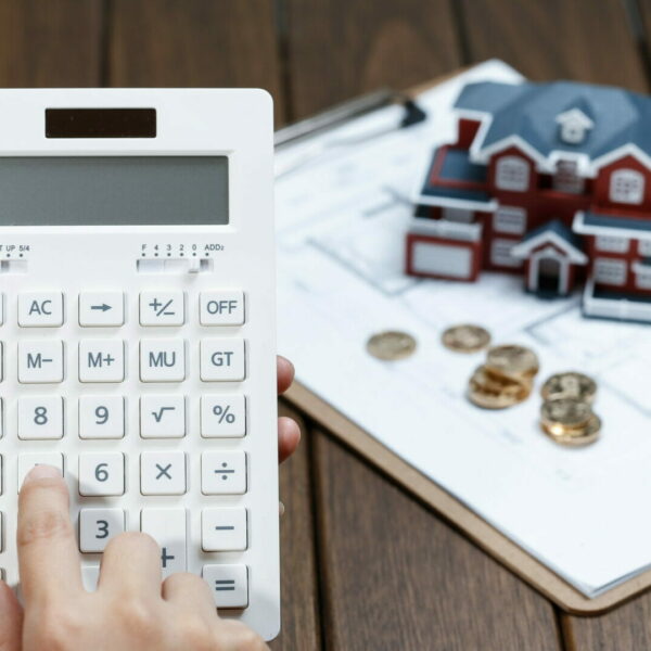 A female hand operating a calculator in front of a Villa house model